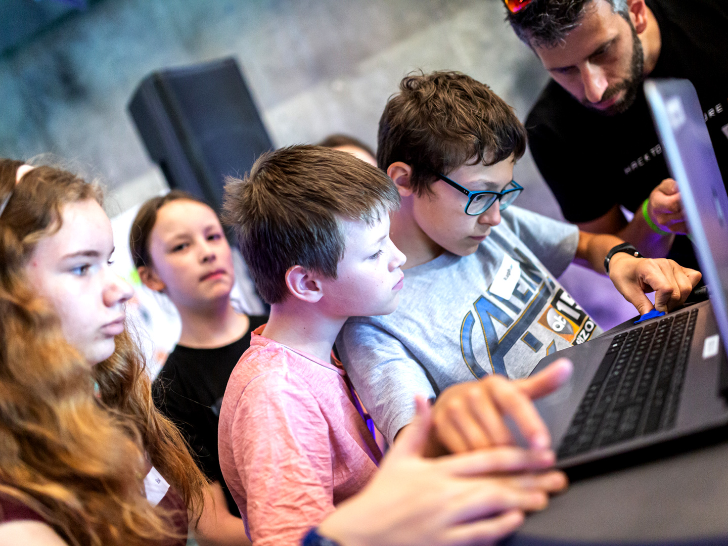 Foto einer Gruppe Kinder, die gemeinsam in einen Laptop blicken.