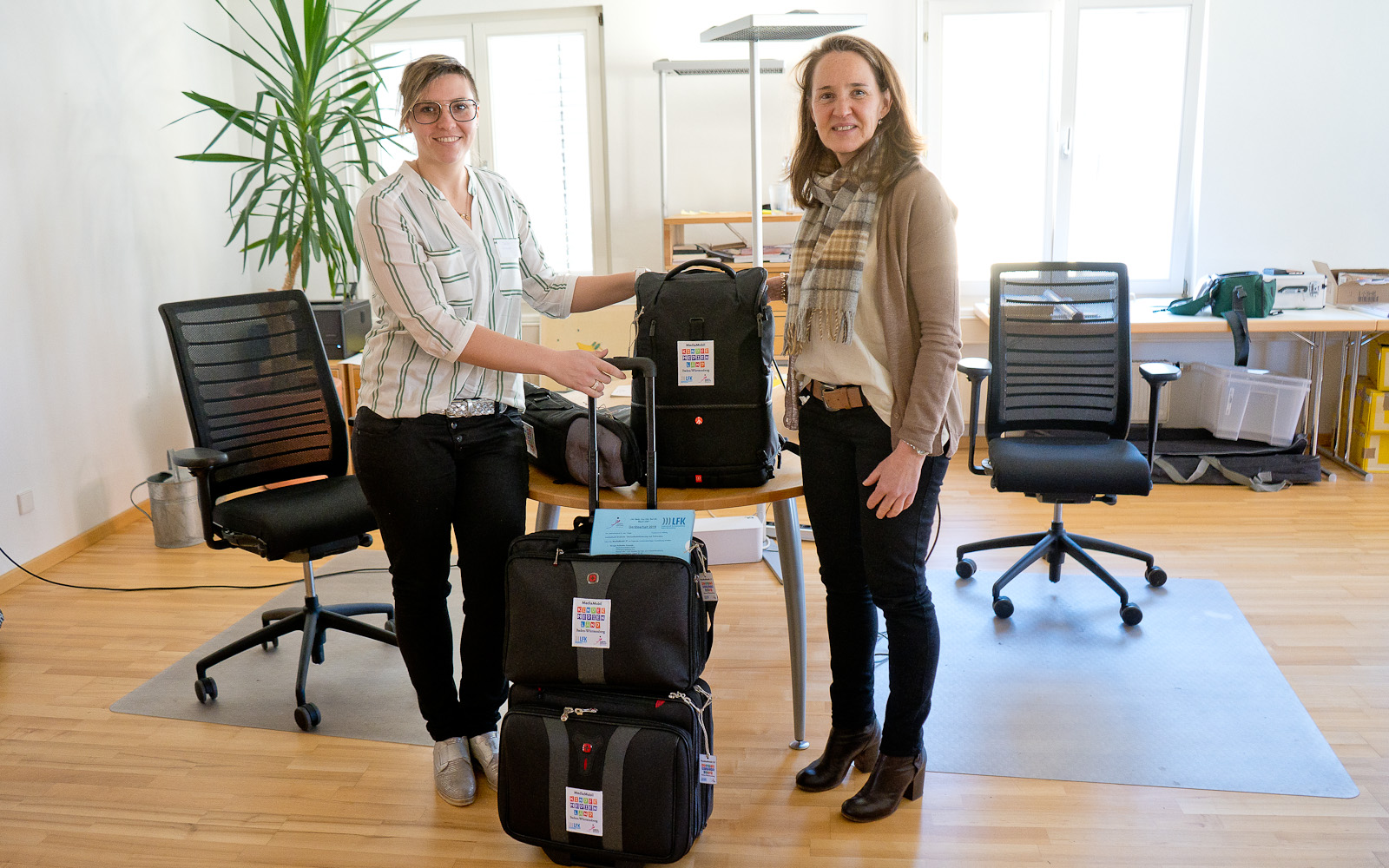 Foto von zwei Personen mit Koffern und Taschen.