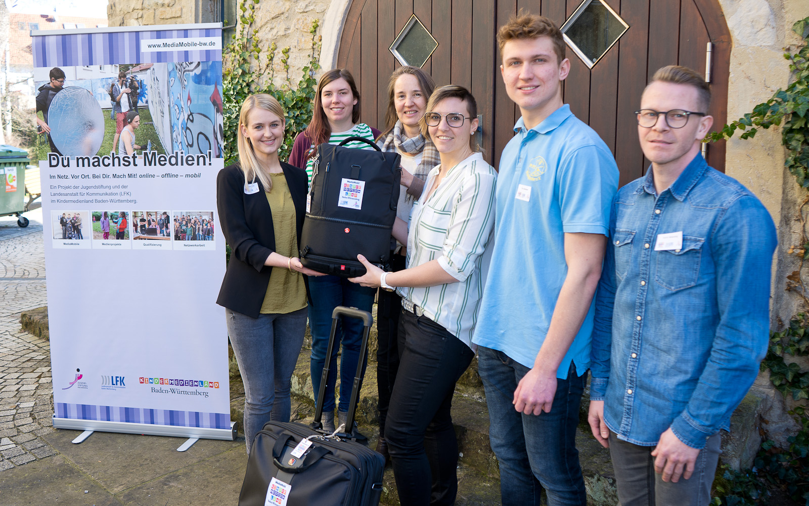 Foto von einer Personengruppe mit Koffern und Taschen.
