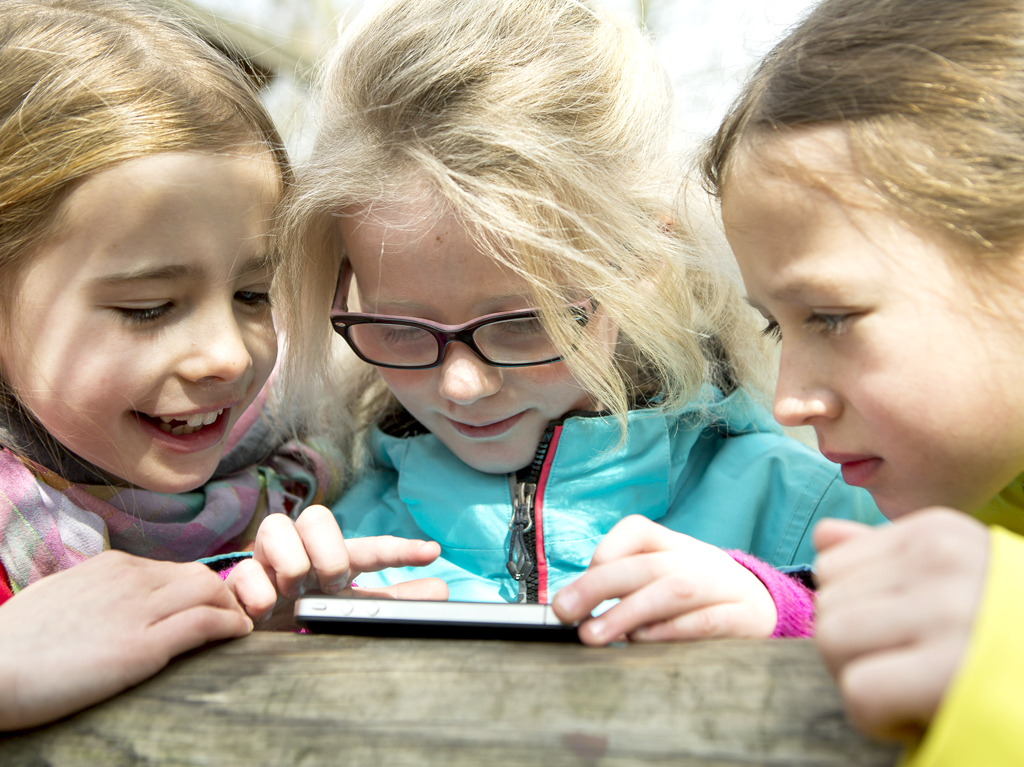 Drei Mädchen blicken auf ein Smartphone