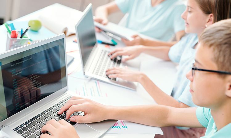 Schülerinnen und Schüler arbeiten im Klassenzimmer an Laptops