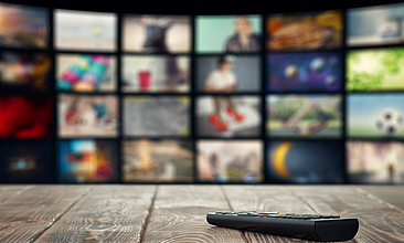 Fernbedienung liegt vor Smart-TV. Auf dem Bildschirm sind mehrere Apps zu sehen.