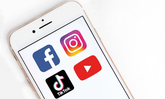 Smartphone mit Logos von Facebook, Instagram, TikTok und YouTube.
