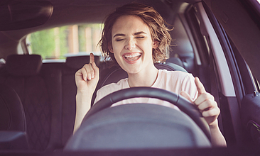 Foto einer fröhlichen jungen Frau im Auto