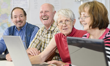 Gruppe älterer Personen schaut auf ein Notebook