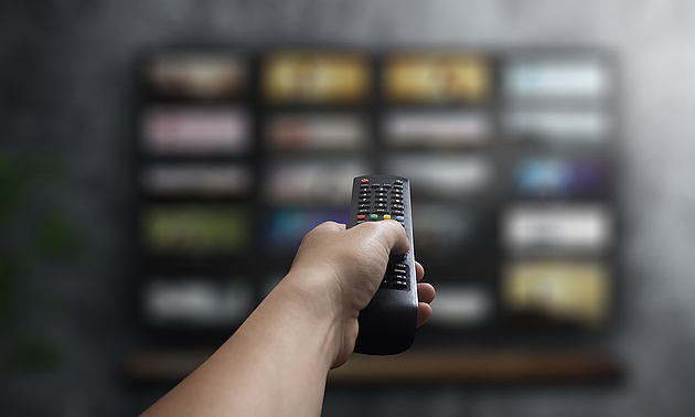 Eine Person bedient mit einer Fernbedienung einen Fernseher