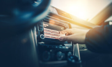 Foto einer Hand, die ein Autoradio bedient