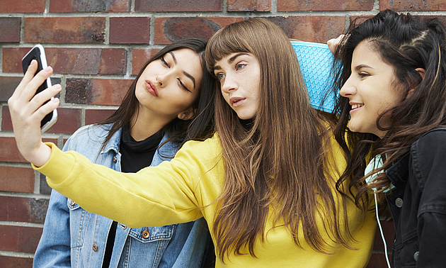 Foto von drei jungen Frauen, die mit dem Smartphone ein Selfie schießen