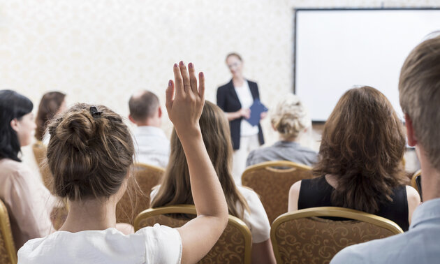 Eine junge Frau meldet sich in einem Seminar zu Wort