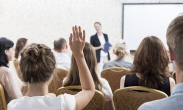 Eine junge Frau meldet sich in einem Seminar zu Wort