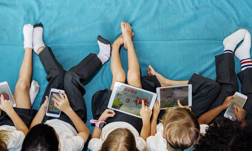 Foto einer Gruppe von Kindern, die auf Tablets schauen