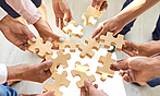 Viele Hände fügen Puzzleteile zusammen